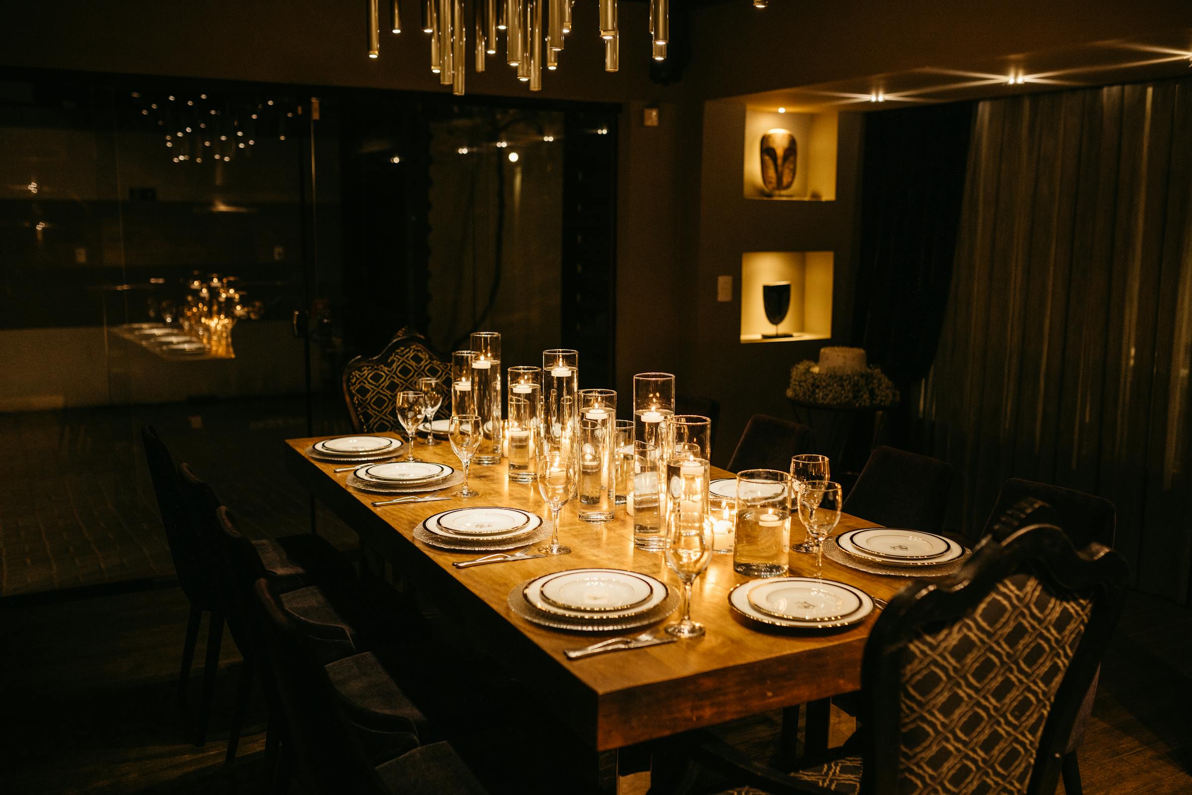 Warm candlelit private dining room with long table, floating candles and pendant lighting