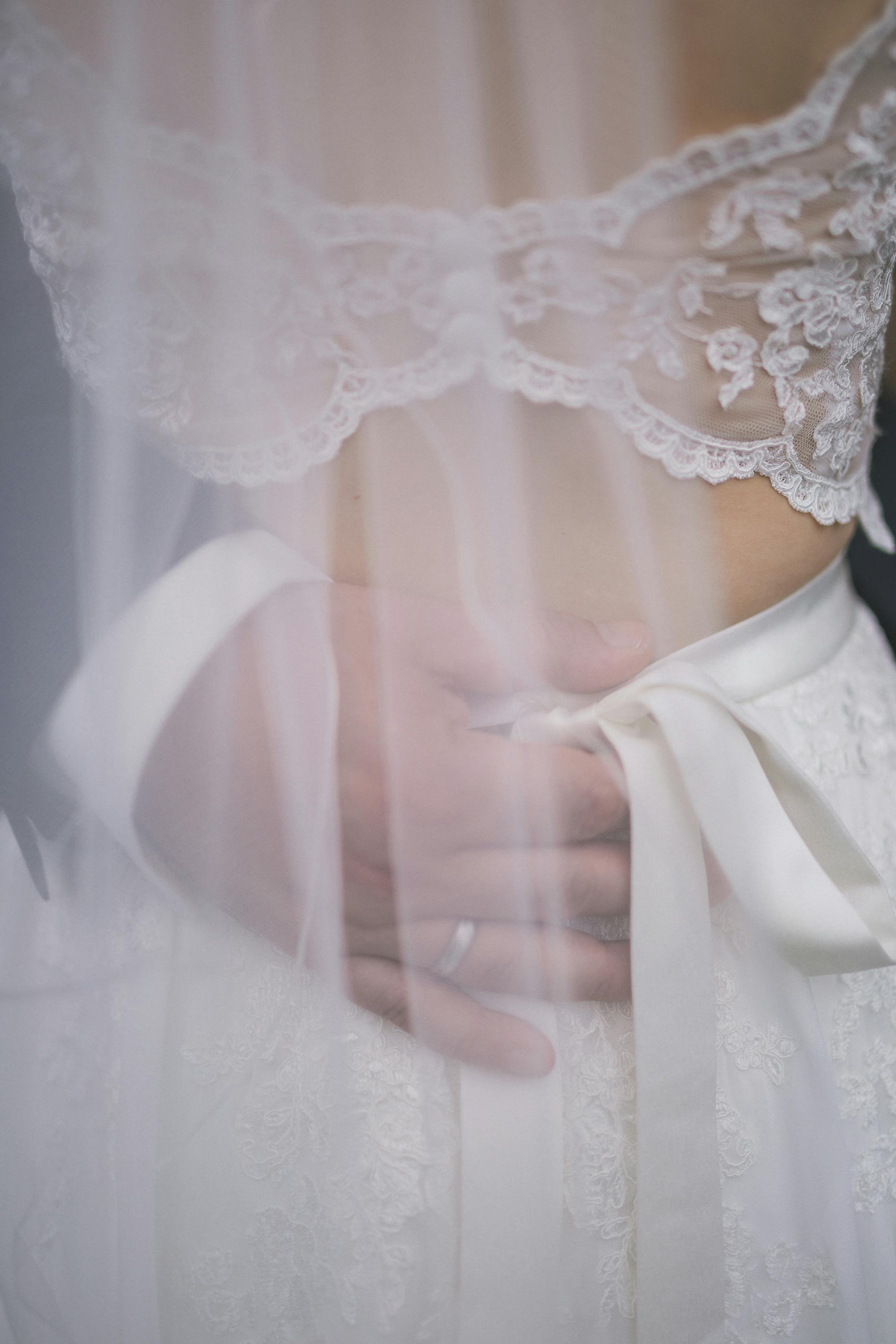 Groom holding the bride's hand on her dress