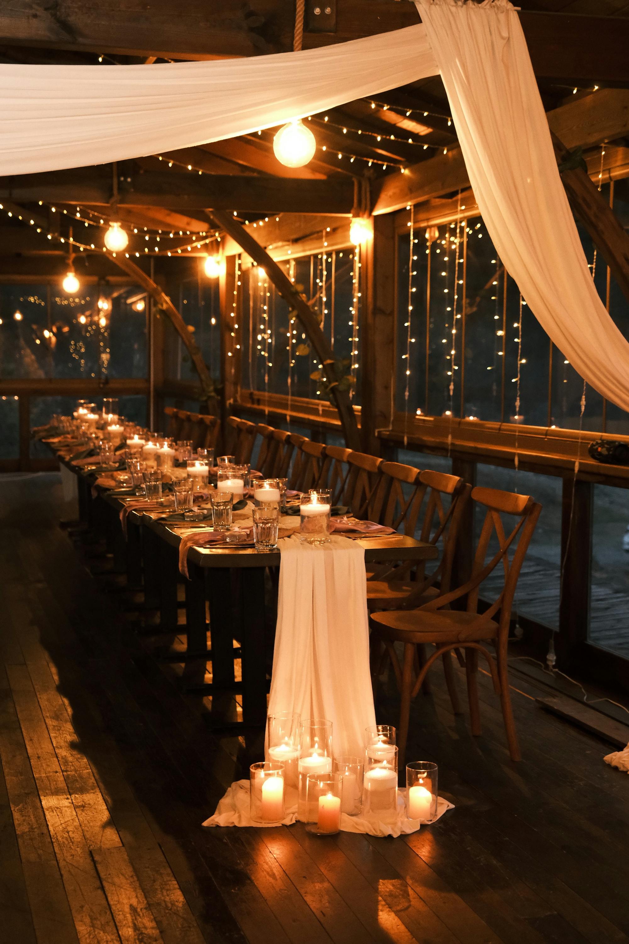 Long candlelit wedding reception with draped fabric and string lights