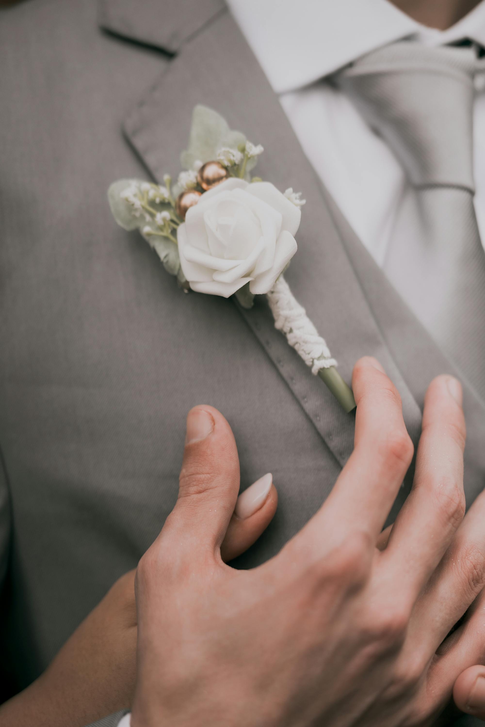 White rose boutonniere on a groom's grey suit