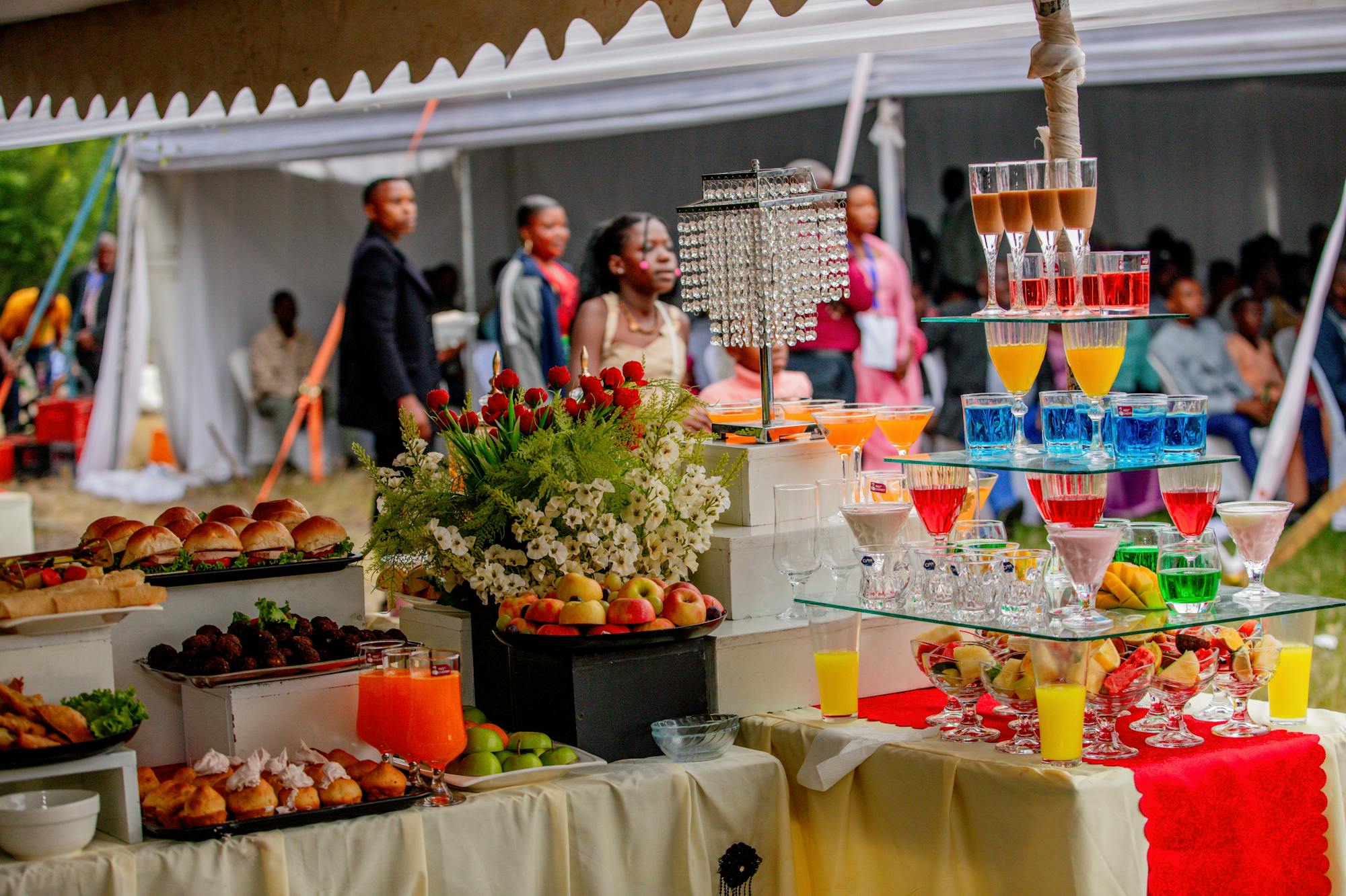 Vibrant outdoor event catering setup with colourful buffet, juice tower and fresh fruits
