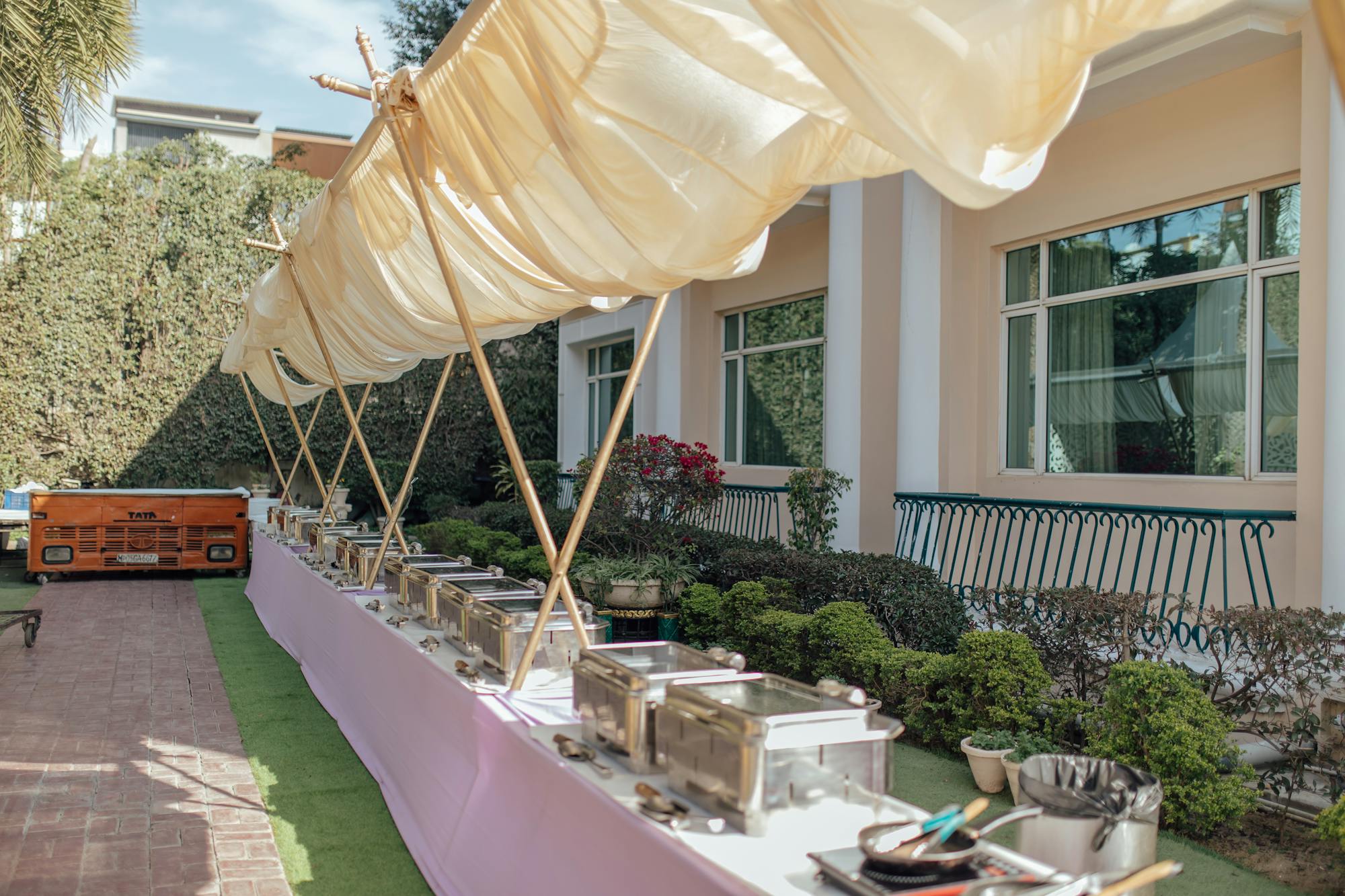 Outdoor buffet with chafing dishes under a draped canopy