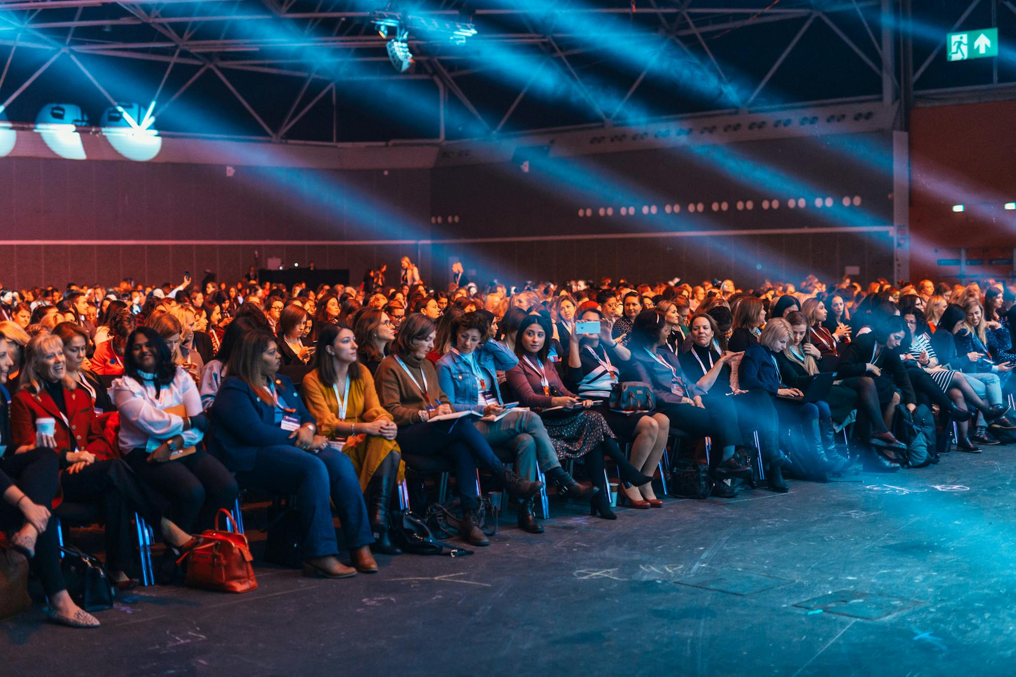 Large corporate conference auditorium lit by dramatic blue stage lighting