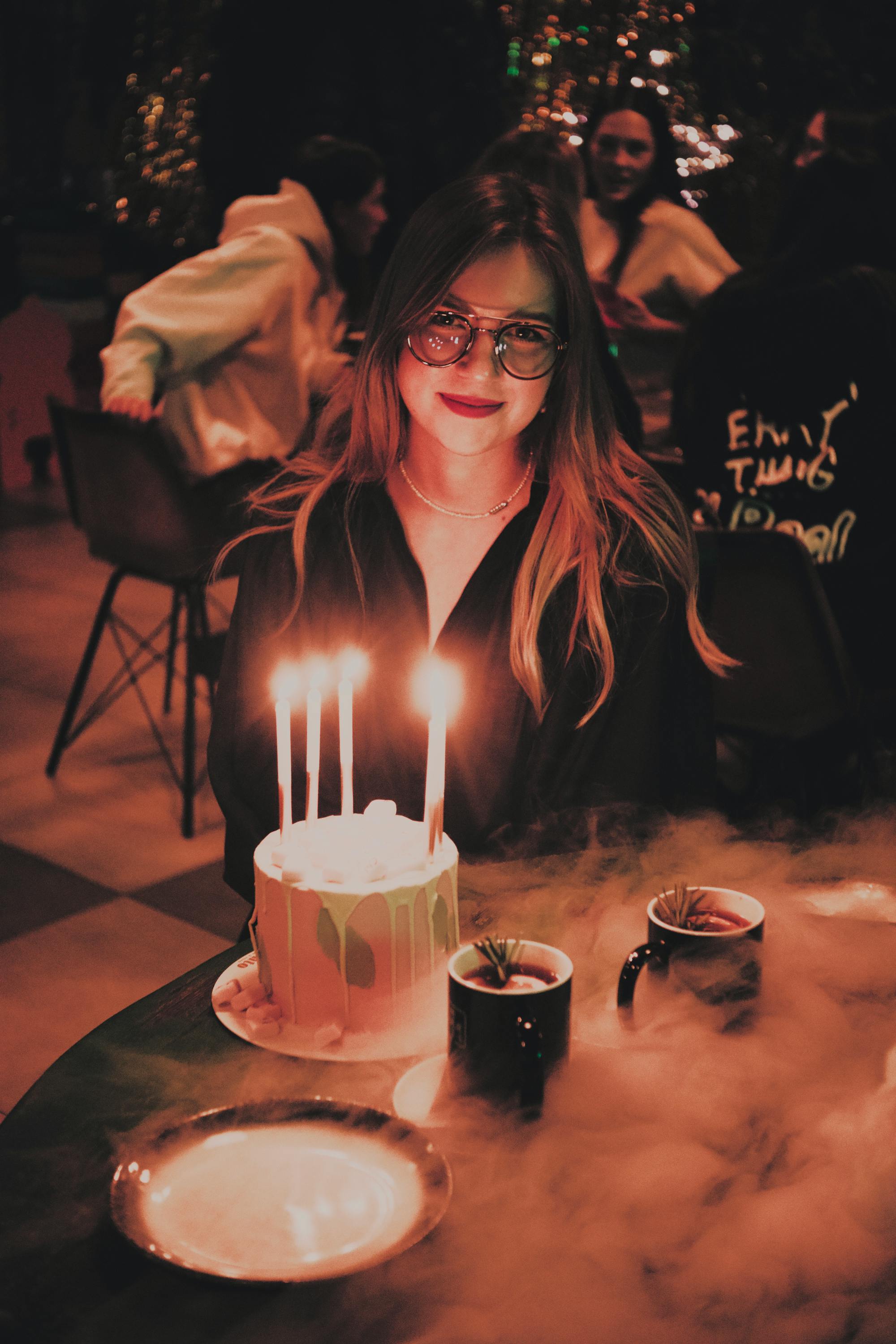 Woman with sparkler-lit cake at a moody birthday celebration