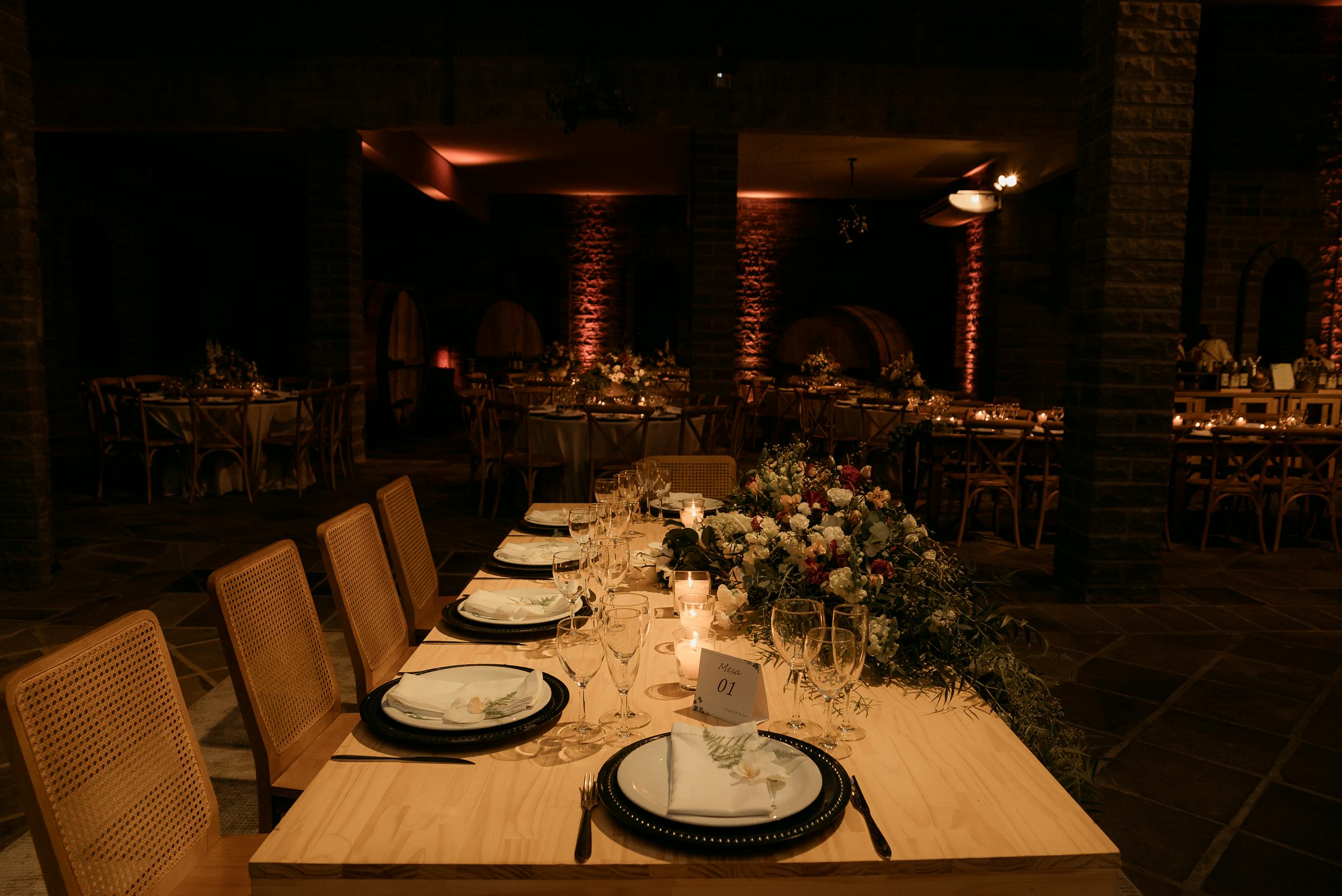 Candlelit wedding reception with floral runner and crossback chairs in a warm brick venue