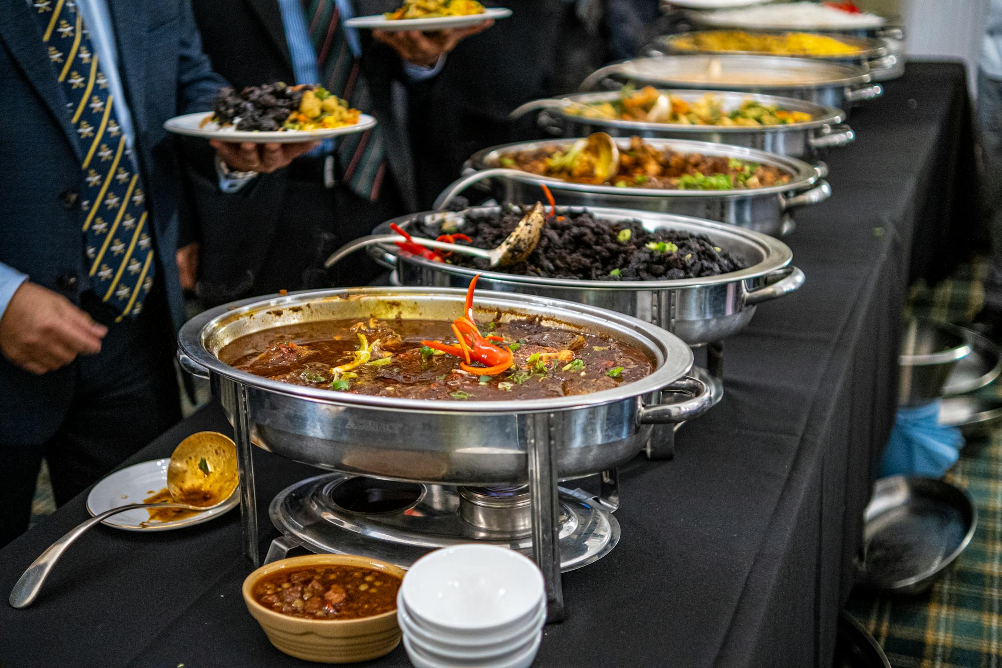 Guests in business attire serving themselves from a row of hot chafing dishes